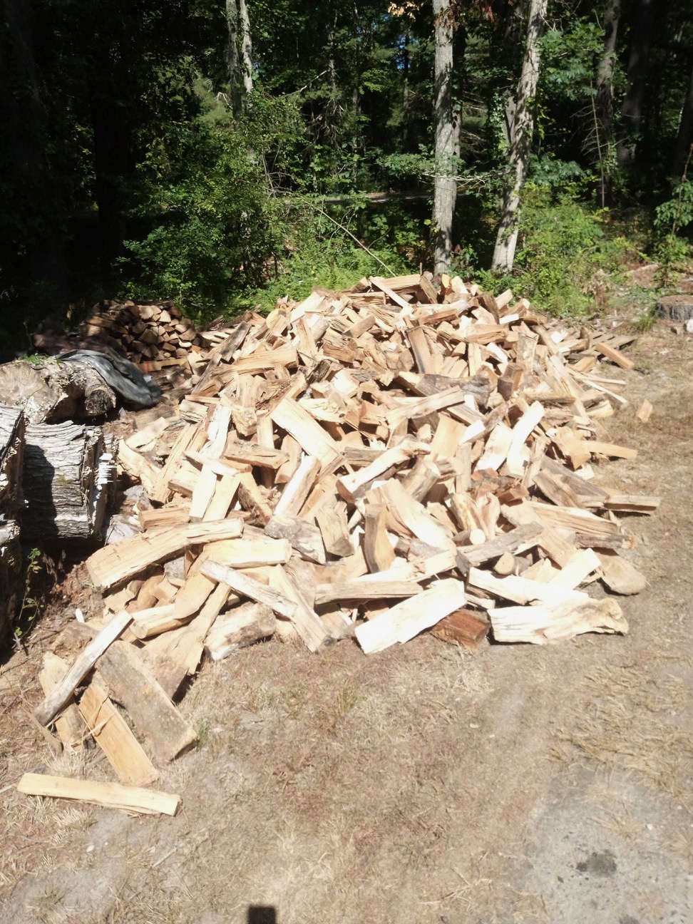 Large pile of delivered split firewood on a customer’s lawn