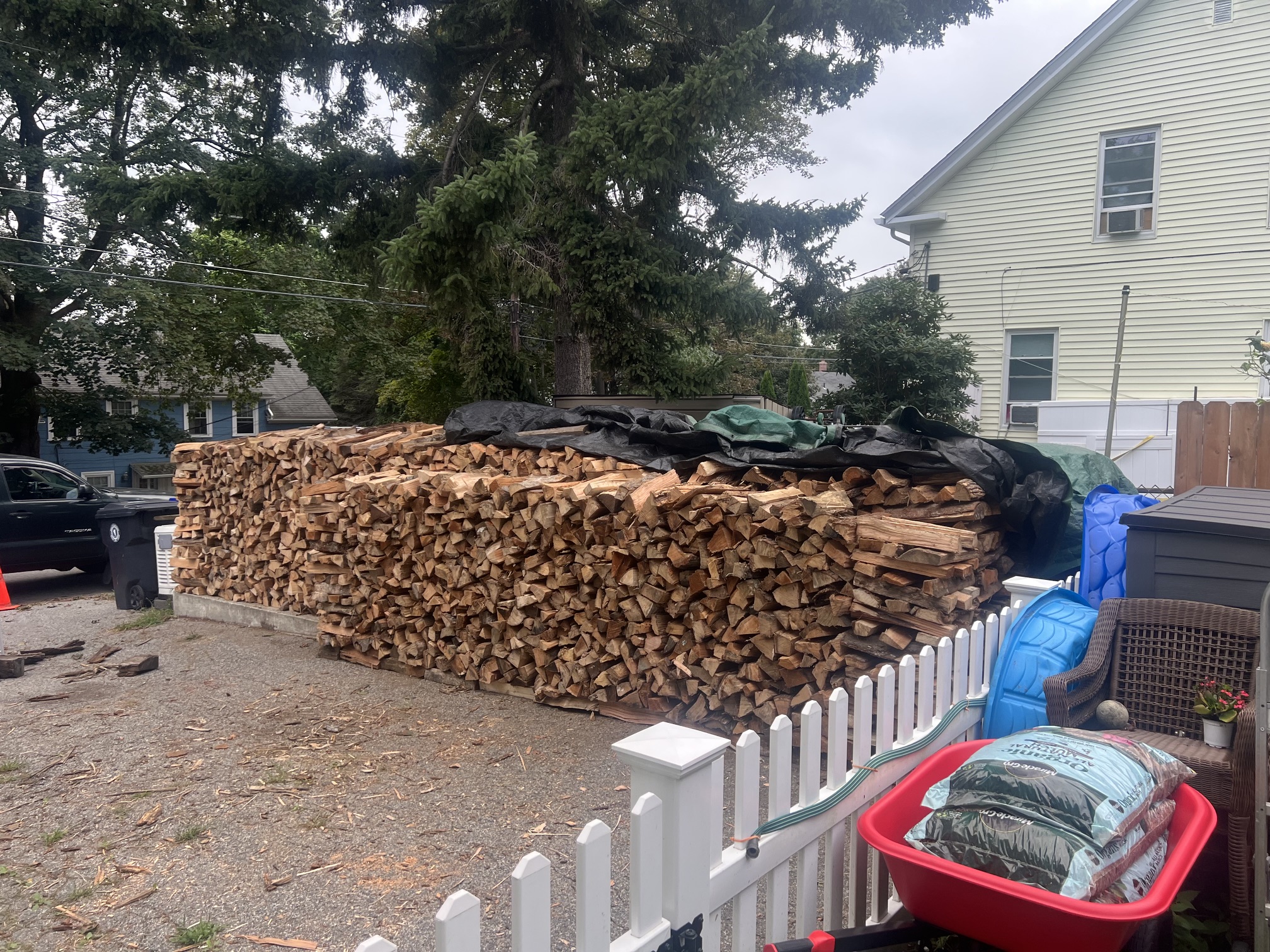 Seasoned firewood delivery arranged beside a customer’s home