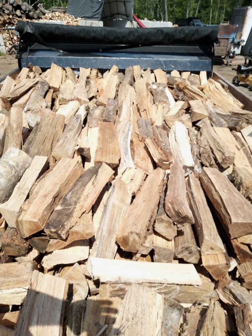 Close-up of freshly split seasoned hardwood firewood filling the truck body at Cote Landscape