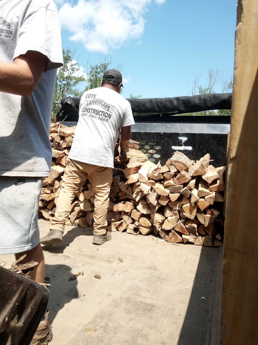 Cote Landscape crew in company t-shirts loading firewood into the delivery truck