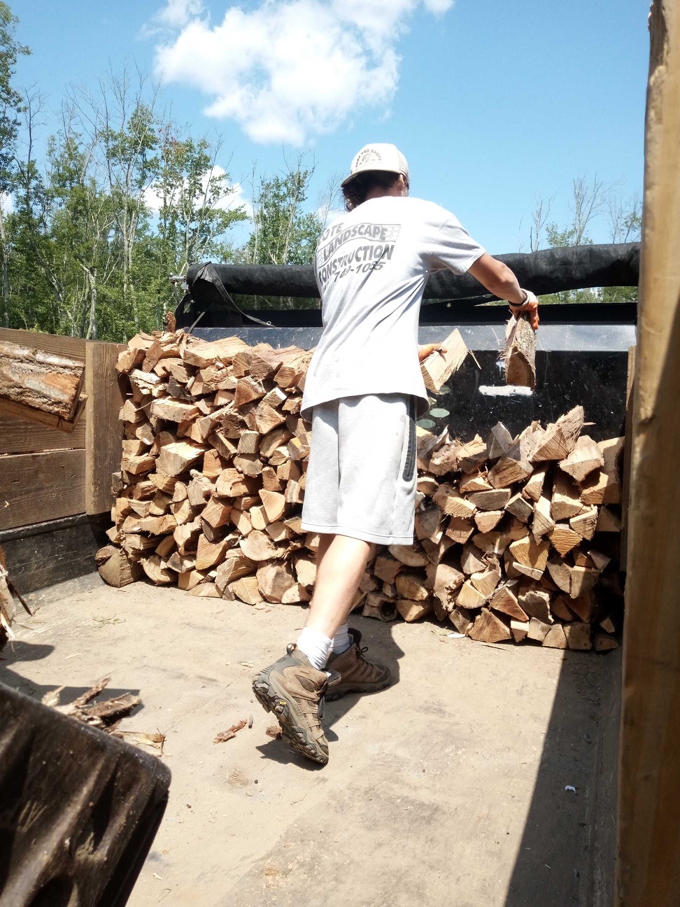 Cote Landscape crew member pulling the tarp over a loaded firewood delivery truck