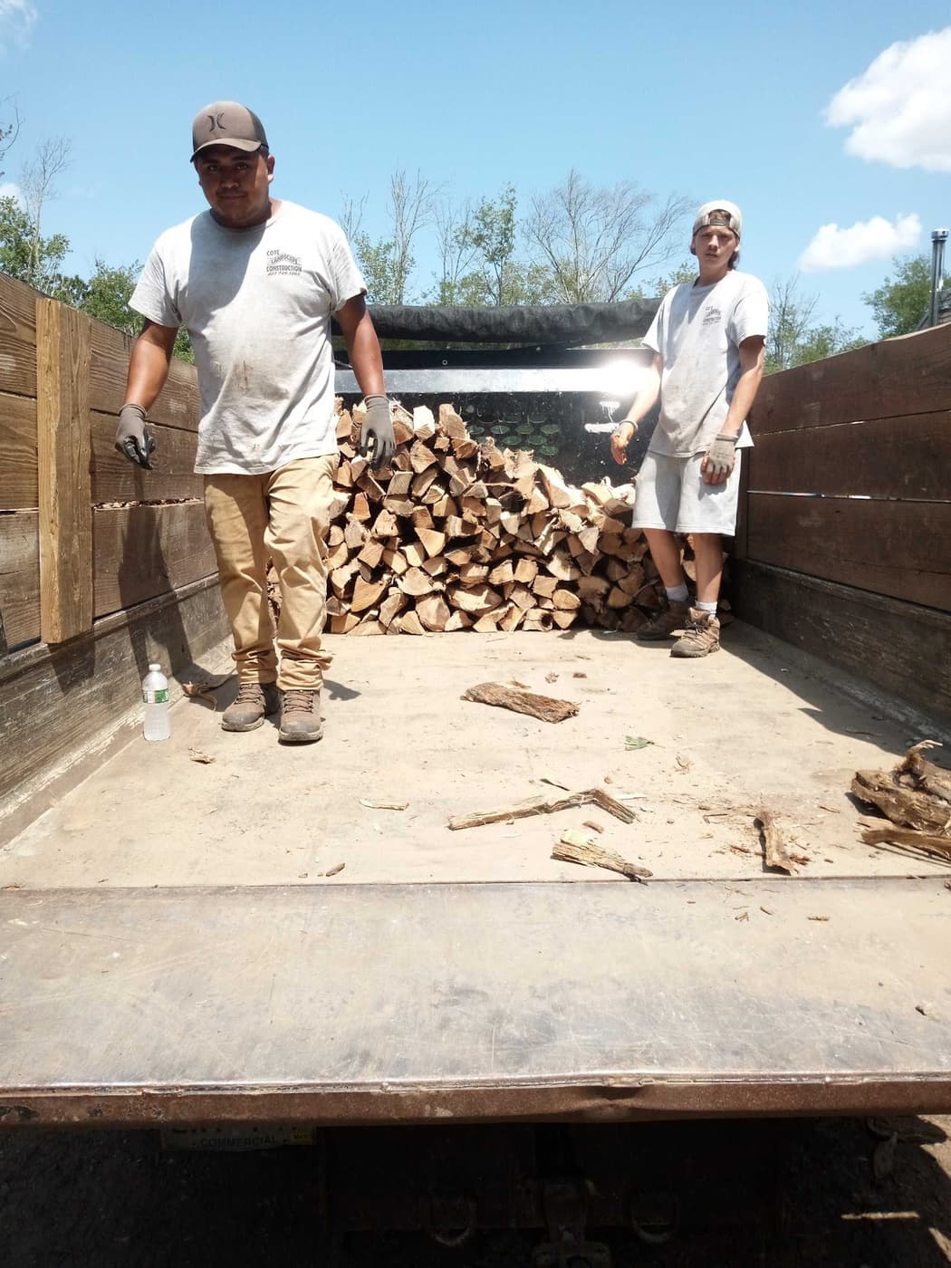 Two Cote Landscape crew members standing at the back of the loaded firewood delivery truck